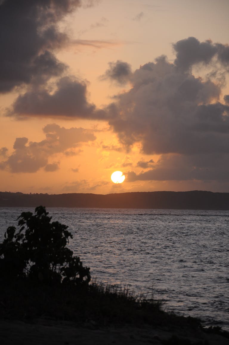 Experience the serene sunset at Le Moule, Grande-Terre, Guadeloupe with vibrant orange skies and tranquil waters.